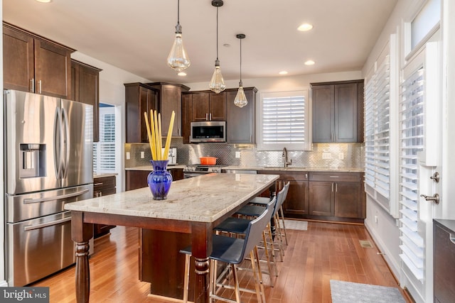 6139 Sligo Mill Rd NE, Washington, DC 20011 - kitchen featuring appliances with stainless steel finishes, a sink, dark brown cabinets, light wood finished floors, and recessed lighting