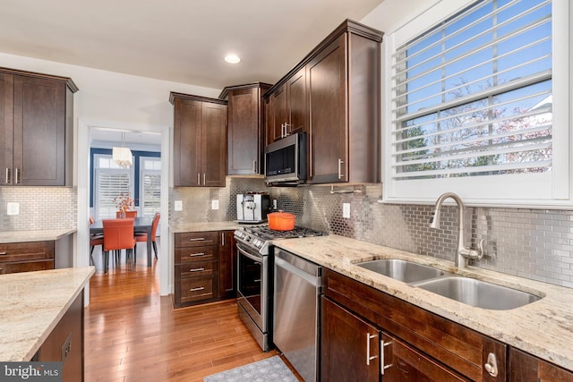 6139 Sligo Mill Rd NE, Washington, DC 20011 - kitchen featuring appliances with stainless steel finishes, a sink, light wood finished floors, light stone countertops, and dark brown cabinetry