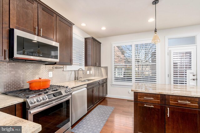 6139 Sligo Mill Rd NE, Washington, DC 20011 - kitchen with stainless steel appliances, dark brown cabinets, wood finished floors, light stone countertops, and tasteful backsplash