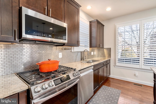 6139 Sligo Mill Rd NE, Washington, DC 20011 - kitchen featuring appliances with stainless steel finishes, dark brown cabinets, baseboards, a sink, and light stone counters