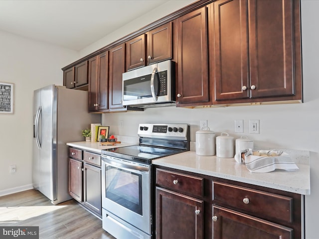 251 Magellan Dr, Martinsburg, WV 25404 - kitchen featuring appliances with stainless steel finishes, light wood finished floors, light stone countertops, and dark brown cabinets