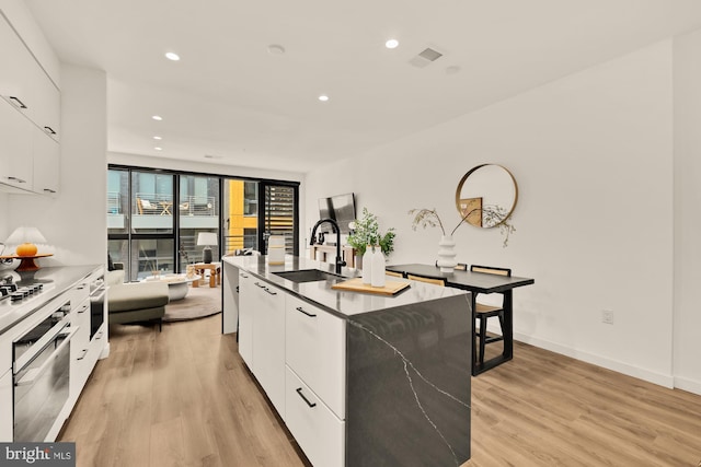 1500 Harry Thomas Way NE Unit 504, Washington, DC 20002 - kitchen featuring modern cabinets, stainless steel oven, white cabinets, light wood finished floors, and a center island with sink