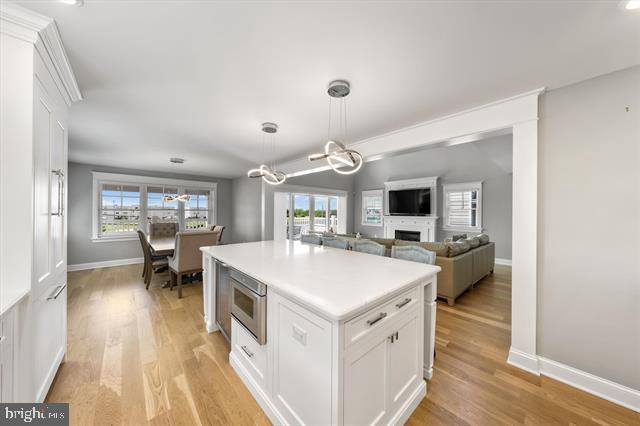 1005 Dune Dr, Avalon, NJ 08202 - kitchen featuring white cabinetry, light wood finished floors, a chandelier, and plenty of natural light