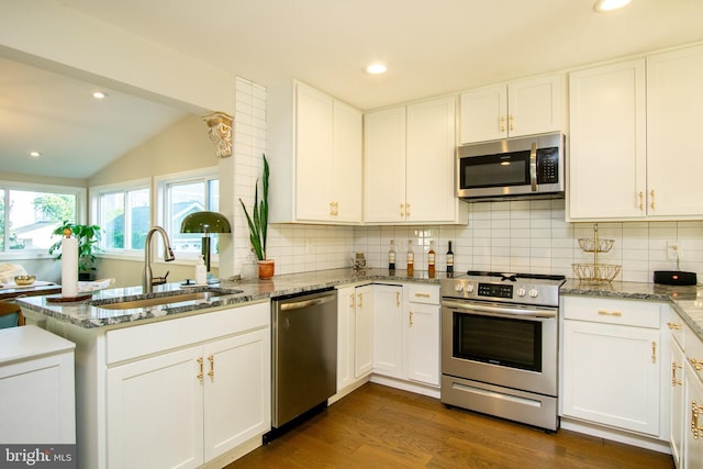 9007 Millers Island Blvd, Baltimore, MD 21219 - kitchen featuring stainless steel appliances, lofted ceiling, a peninsula, backsplash, and white cabinets