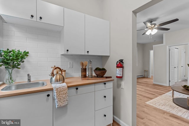 72 River St, Browns Mills, NJ 08015 - kitchen featuring decorative backsplash, white cabinetry, light wood-style floors, ceiling fan, and baseboard heating