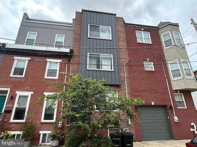 1002 S Colorado St, Philadelphia, PA 19146 - view of front facade with board and batten siding, brick siding, a garage, and driveway