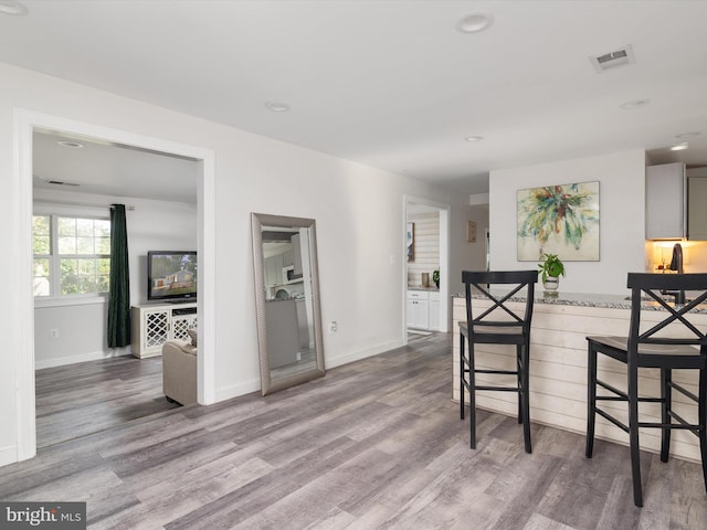 7802 Gary Ln, Severn, MD 21144 - kitchen with wood finished floors, a breakfast bar area, recessed lighting, and light stone countertops