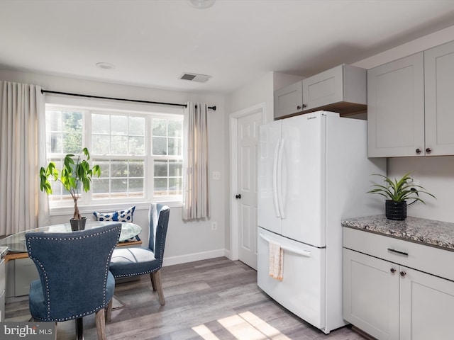 7802 Gary Ln, Severn, MD 21144 - kitchen with freestanding refrigerator, healthy amount of natural light, light wood finished floors, and light stone countertops