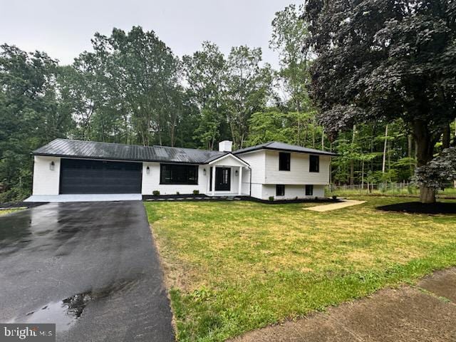 654 Devonshire Dr, State College, PA 16803 - tri-level home with asphalt driveway, a garage, view of wooded area, and a front yard