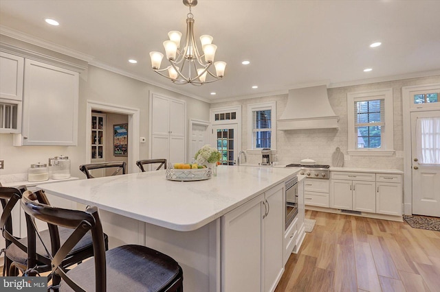 2165 Broadway, Hanover, PA 17331 - kitchen with custom range hood, a breakfast bar, ornamental molding, a chandelier, and light wood finished floors