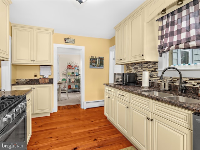 414 S Aurora St, Easton, MD 21601 - kitchen featuring cream cabinetry, baseboard heating, gas range, and light wood-style floors