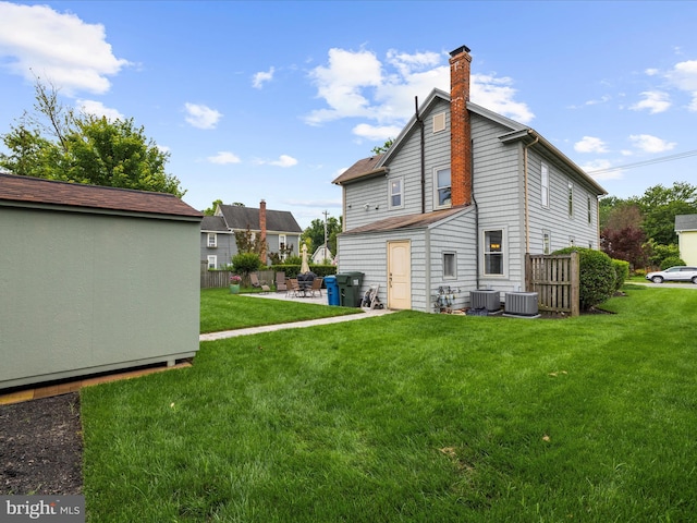 414 S Aurora St, Easton, MD 21601 - back of property featuring a yard, a chimney, a patio, and a storage unit