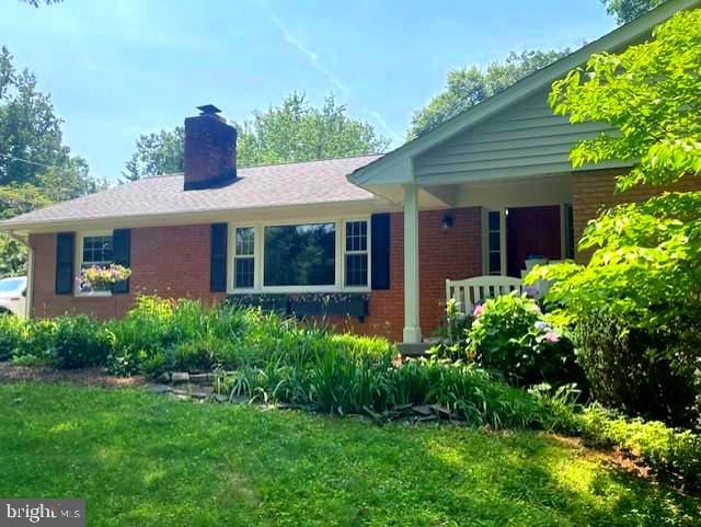 10704 Montgomery Dr, Manassas, VA 20111 - view of property exterior with brick siding, a chimney, and a yard