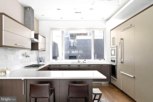 204 W Laurel St Unit 3, Philadelphia, PA 19123 - kitchen with appliances with stainless steel finishes, wall chimney range hood, a peninsula, dark wood finished floors, and a breakfast bar