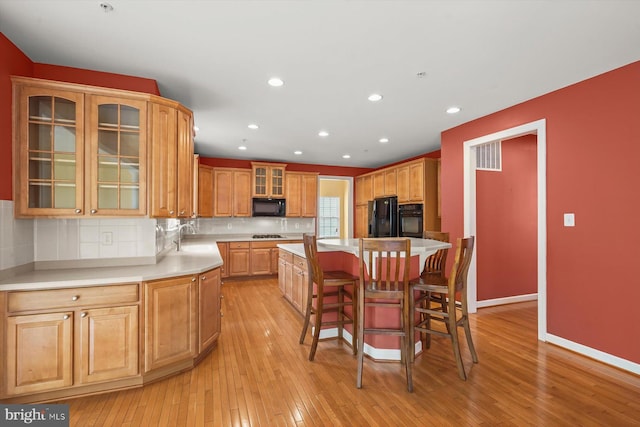 14014 Mary Bowie Pkwy, Upper Marlboro, MD 20774 - kitchen featuring black appliances, a center island, recessed lighting, a breakfast bar area, and light wood-type flooring