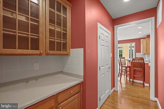 14014 Mary Bowie Pkwy, Upper Marlboro, MD 20774 - kitchen featuring light wood finished floors, tasteful backsplash, light countertops, glass insert cabinets, and recessed lighting