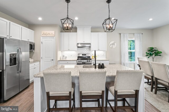 57 Oak Ln, Carneys Point, NJ 08069 - kitchen with appliances with stainless steel finishes, under cabinet range hood, decorative backsplash, white cabinetry, and an island with sink