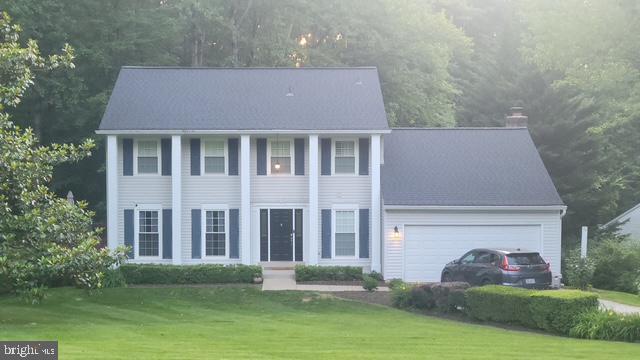 6309 Ember Ct, Manassas, VA 20112 - greek revival house with an attached garage, a chimney, and a front lawn