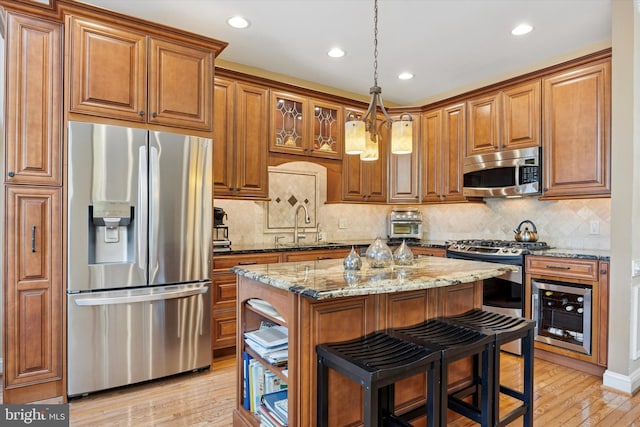 272 Center Point Ln, Lansdale, PA 19446 - kitchen featuring appliances with stainless steel finishes, wine cooler, a kitchen island, brown cabinets, and light stone countertops