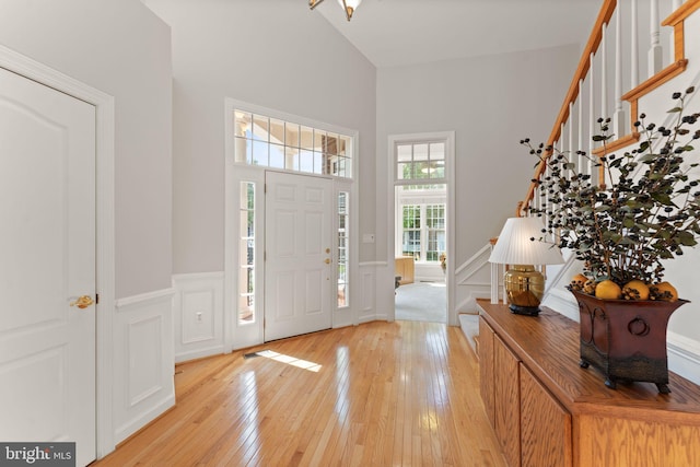 43665 Jernigan Ter, Leesburg, VA 20176 - entryway featuring stairway, light wood finished floors, a wainscoted wall, a decorative wall, and a towering ceiling