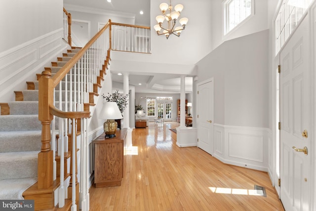 43665 Jernigan Ter, Leesburg, VA 20176 - entryway featuring stairway, light wood-style flooring, a chandelier, wainscoting, and a decorative wall