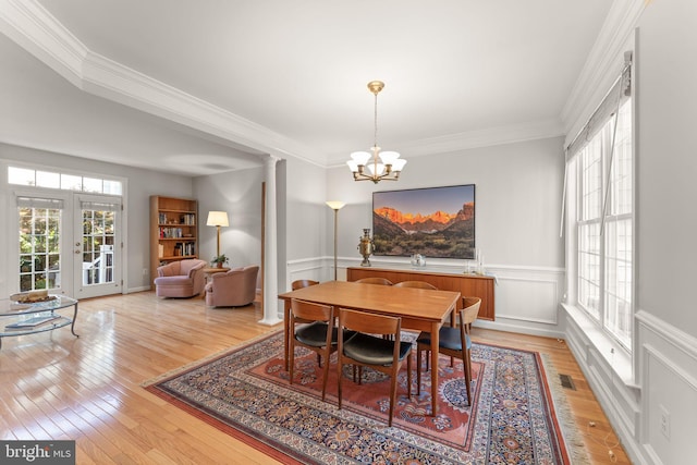 43665 Jernigan Ter, Leesburg, VA 20176 - dining area with crown molding, a chandelier, light wood-style flooring, a wainscoted wall, and decorative columns