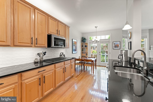 43665 Jernigan Ter, Leesburg, VA 20176 - kitchen with stainless steel microwave, tasteful backsplash, light wood-type flooring, a chandelier, and hanging light fixtures
