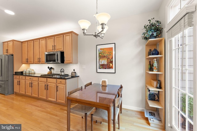 43665 Jernigan Ter, Leesburg, VA 20176 - kitchen featuring stainless steel appliances, a chandelier, dark countertops, light wood-type flooring, and decorative backsplash