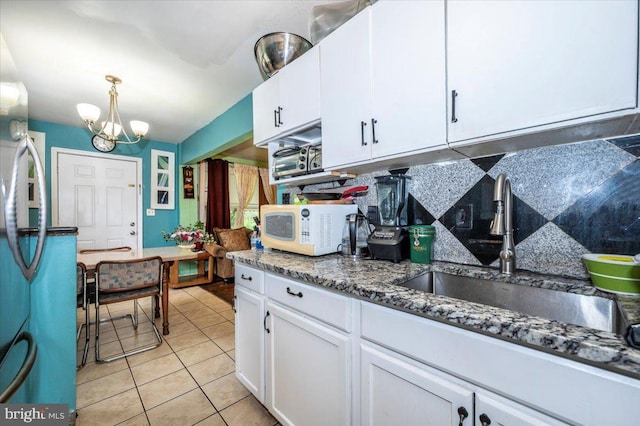 6612 Stockton Ln, Hyattsville, MD 20784 - kitchen with white microwave, a chandelier, white cabinetry, tasteful backsplash, and light tile patterned floors