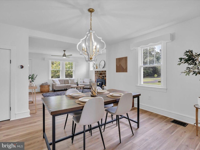 69 Mary Elmer Dr, Bridgeton, NJ 08302 - dining room with light wood finished floors, a chandelier, a stone fireplace, and a ceiling fan