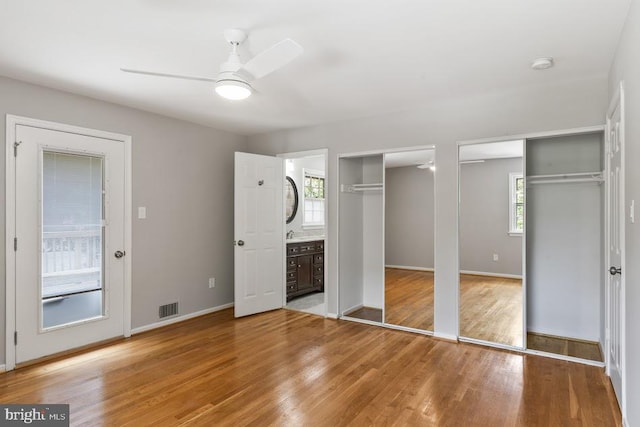 1121 Collingwood Rd, Alexandria, VA 22308 - unfurnished bedroom featuring two closets, wood finished floors, ensuite bath, and ceiling fan