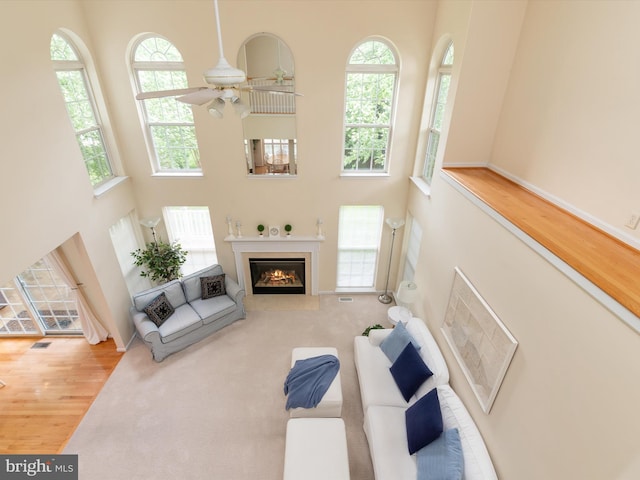 848 Sunny Chapel Rd, Odenton, MD 21113 - living room featuring a towering ceiling, wood finished floors, ceiling fan, and a glass covered fireplace