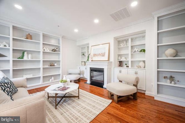 409 S Henry St, Alexandria, VA 22314 - living area with wood finished floors, a fireplace with flush hearth, recessed lighting, ornamental molding, and built in features