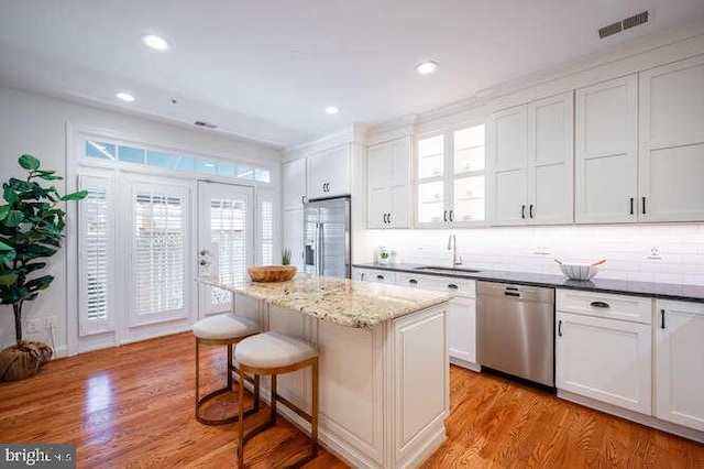 409 S Henry St, Alexandria, VA 22314 - kitchen featuring stainless steel appliances, a center island, a kitchen bar, white cabinets, and light wood-type flooring
