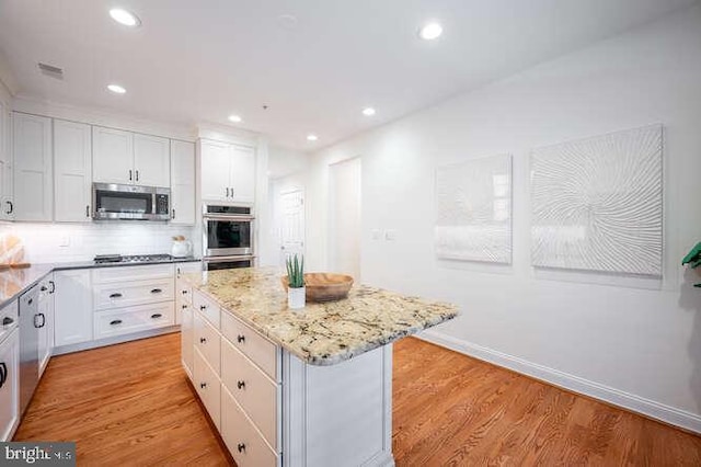 409 S Henry St, Alexandria, VA 22314 - kitchen featuring appliances with stainless steel finishes, a kitchen island, light stone counters, white cabinets, and light wood-type flooring
