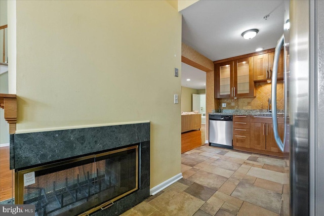 326 Brickhouse Rd, Princeton, NJ 08540 - kitchen featuring appliances with stainless steel finishes, a fireplace, tasteful backsplash, brown cabinetry, and glass insert cabinets