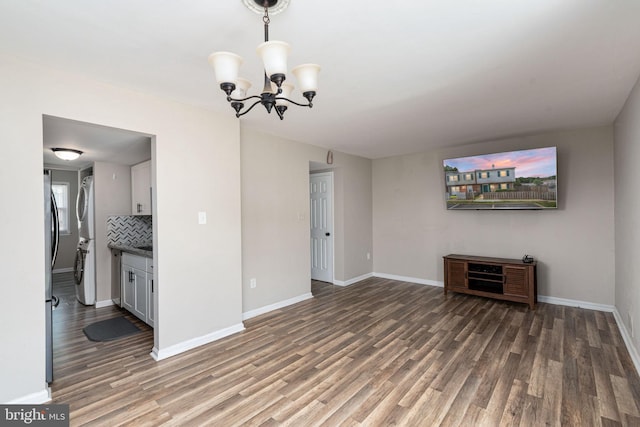 2801 Banks Ct, Dumfries, VA 22026 - unfurnished living room featuring stacked washer and clothes dryer, wood finished floors, and a chandelier