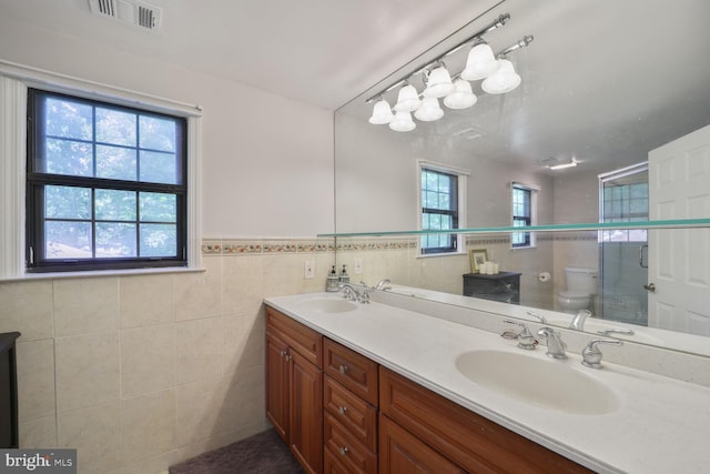 553 Choptank Cove Ct, Annapolis, MD 21401 - bathroom featuring double vanity, tile walls, a wainscoted wall, and a shower with door