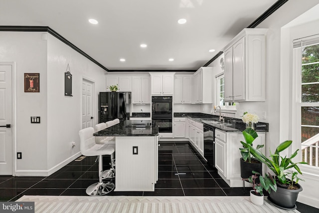 4305 Mulcaster Ter, Dumfries, VA 22025 - kitchen with black appliances, white cabinetry, a kitchen island, dark tile patterned flooring, and a breakfast bar