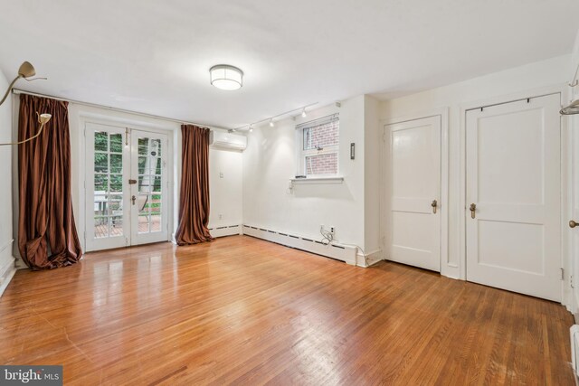 3469 Midvale Ave, Philadelphia, PA 19129 - empty room featuring rail lighting, baseboard heating, light wood finished floors, french doors, and a wall mounted AC
