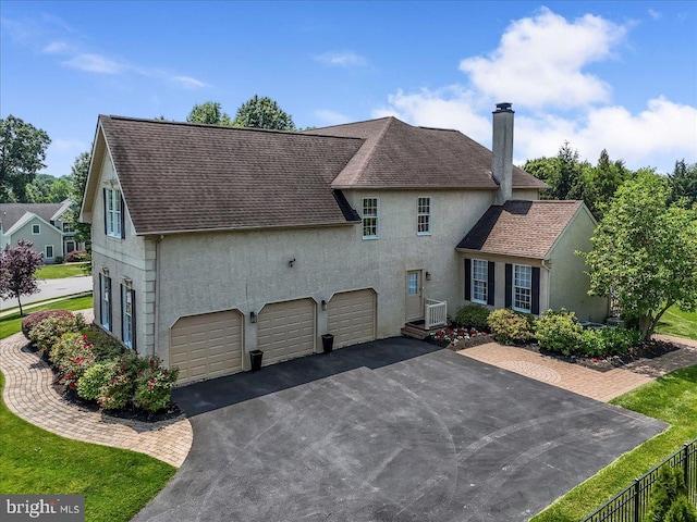 22 Thomas Speakman Dr Unit 76, Glen Mills, PA 19342 - view of side of property featuring stucco siding, a chimney, asphalt driveway, and a garage