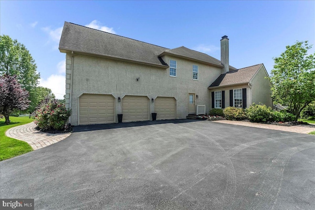 22 Thomas Speakman Dr Unit 76, Glen Mills, PA 19342 - view of front of property with asphalt driveway, stucco siding, an attached garage, and a chimney