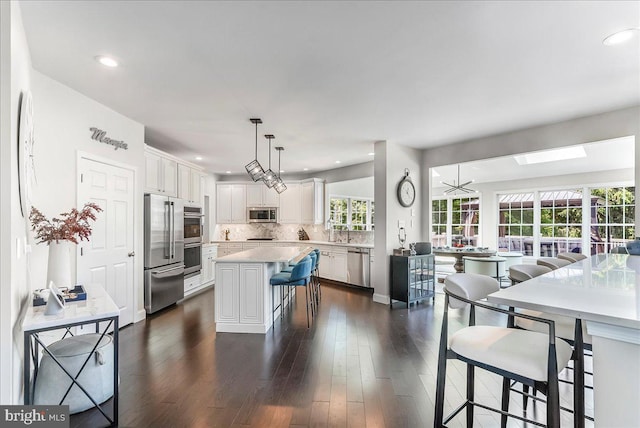 22 Thomas Speakman Dr Unit 76, Glen Mills, PA 19342 - kitchen with stainless steel appliances, white cabinets, light countertops, a breakfast bar, and backsplash