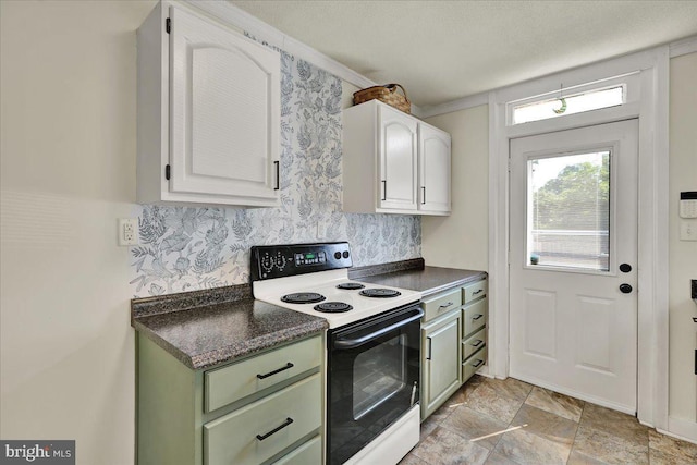 409 N Cherry St, Lancaster, PA 17602 - kitchen with electric range, green cabinets, dark countertops, white cabinets, and light stone finish floors