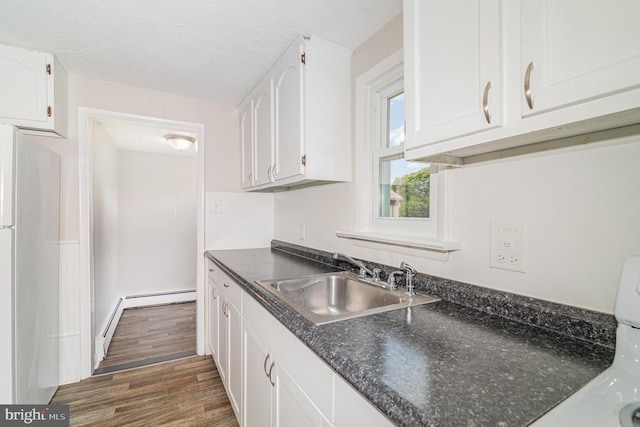 422 N High St, Duncannon, PA 17020 - kitchen featuring white cabinets, dark wood-style flooring, fridge, a baseboard radiator, and a textured ceiling