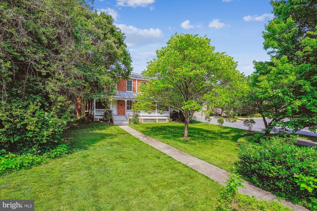 209 E Broad St, Falls Church, VA 22046 - view of property hidden behind natural elements featuring a porch, a front lawn, and brick siding