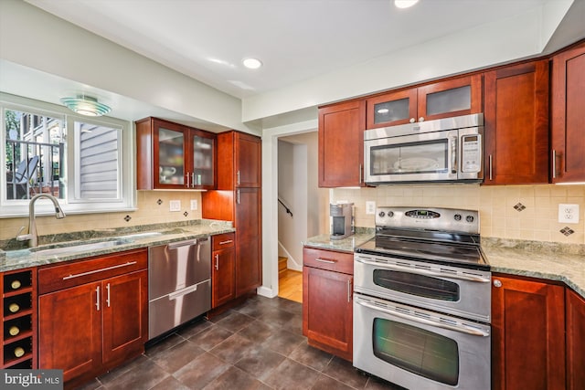 904 Hyde Rd, Silver Spring, MD 20902 - kitchen featuring appliances with stainless steel finishes, reddish brown cabinets, light stone countertops, tasteful backsplash, and glass insert cabinets
