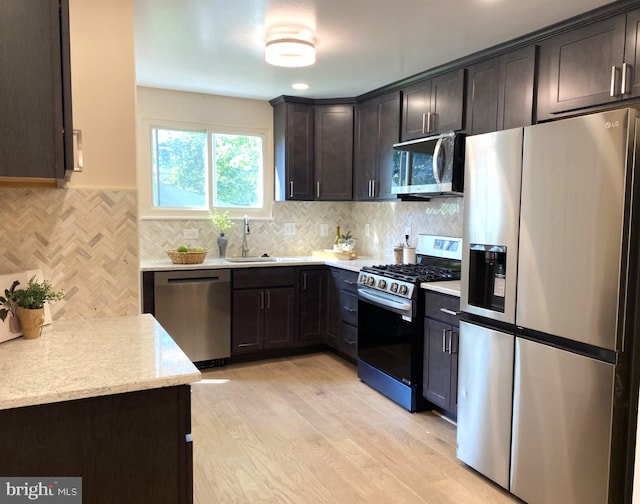 423 Highmeadow Rd, Reisterstown, MD 21136 - kitchen with stainless steel appliances, dark brown cabinets, light wood-type flooring, decorative backsplash, and light stone counters