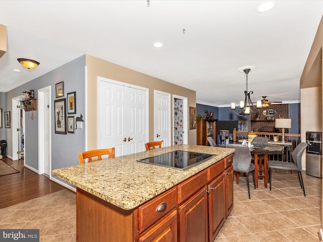 6108 Fieldcrest Dr, Frederick, MD 21701 - kitchen with black electric stovetop, open floor plan, a chandelier, light stone counters, and a center island