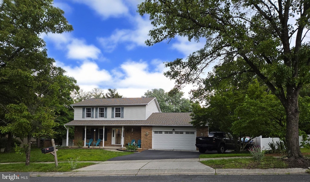 7907 Elberta Dr, Severn, MD 21144 - traditional-style home with a porch, a garage, asphalt driveway, brick siding, and a front yard